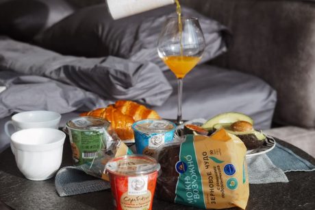 Cozy breakfast setup with croissant, juice, and yogurt on bedside table, creating a relaxing morning vibe.