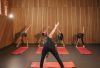 Yoga class with diverse adults stretching on mats in a cozy wooden studio.