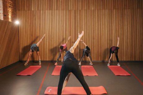 Yoga class with diverse adults stretching on mats in a cozy wooden studio.